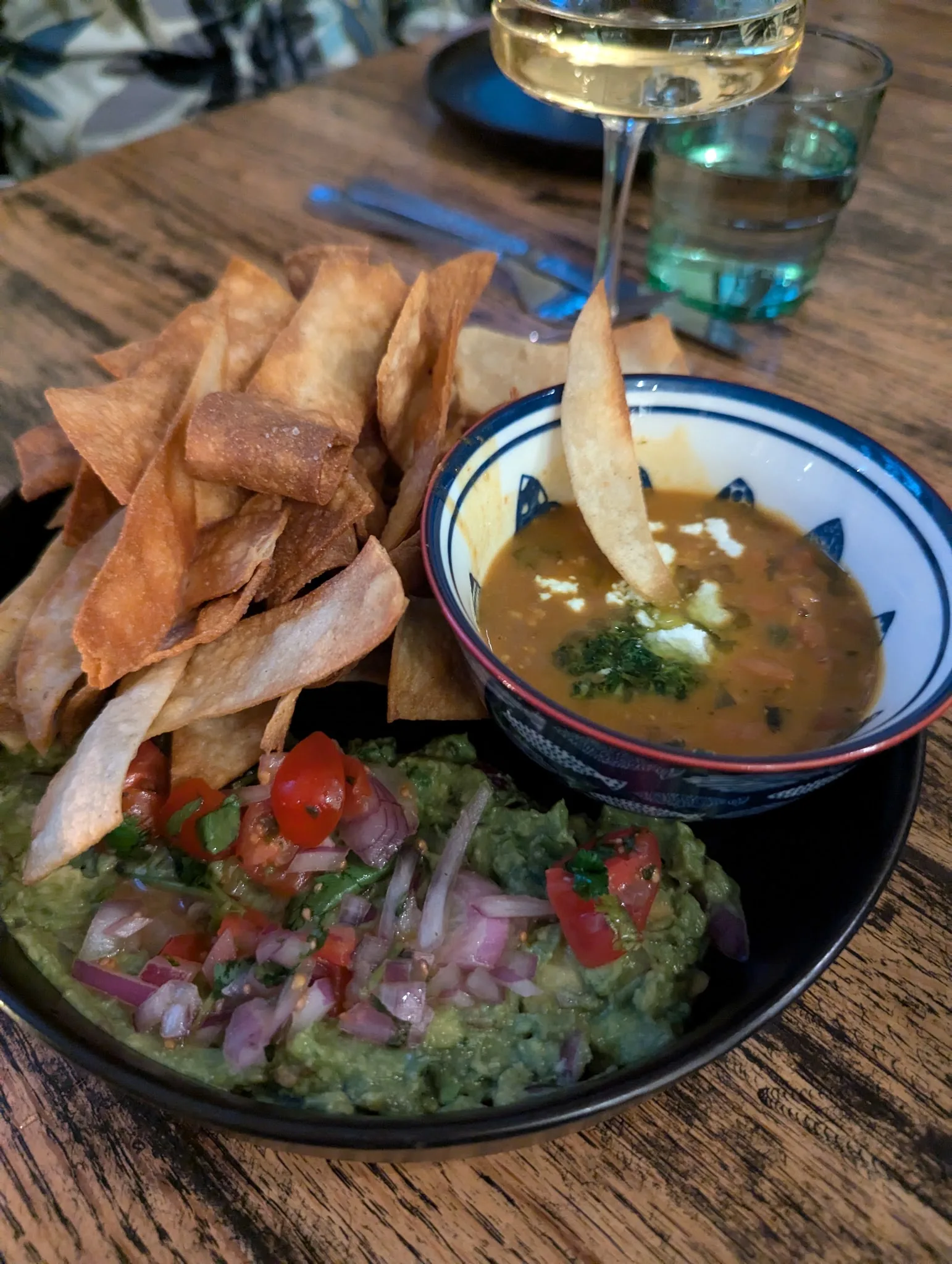 Guacamole and tortilla strips with a glass of white wine