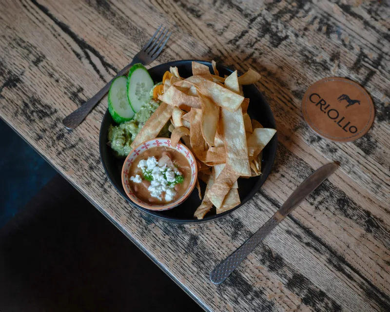 Criollo guacamole with house-made tortilla strips and a branded coaster