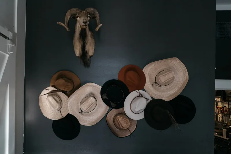 A wall of felt and straw hats against dark paint