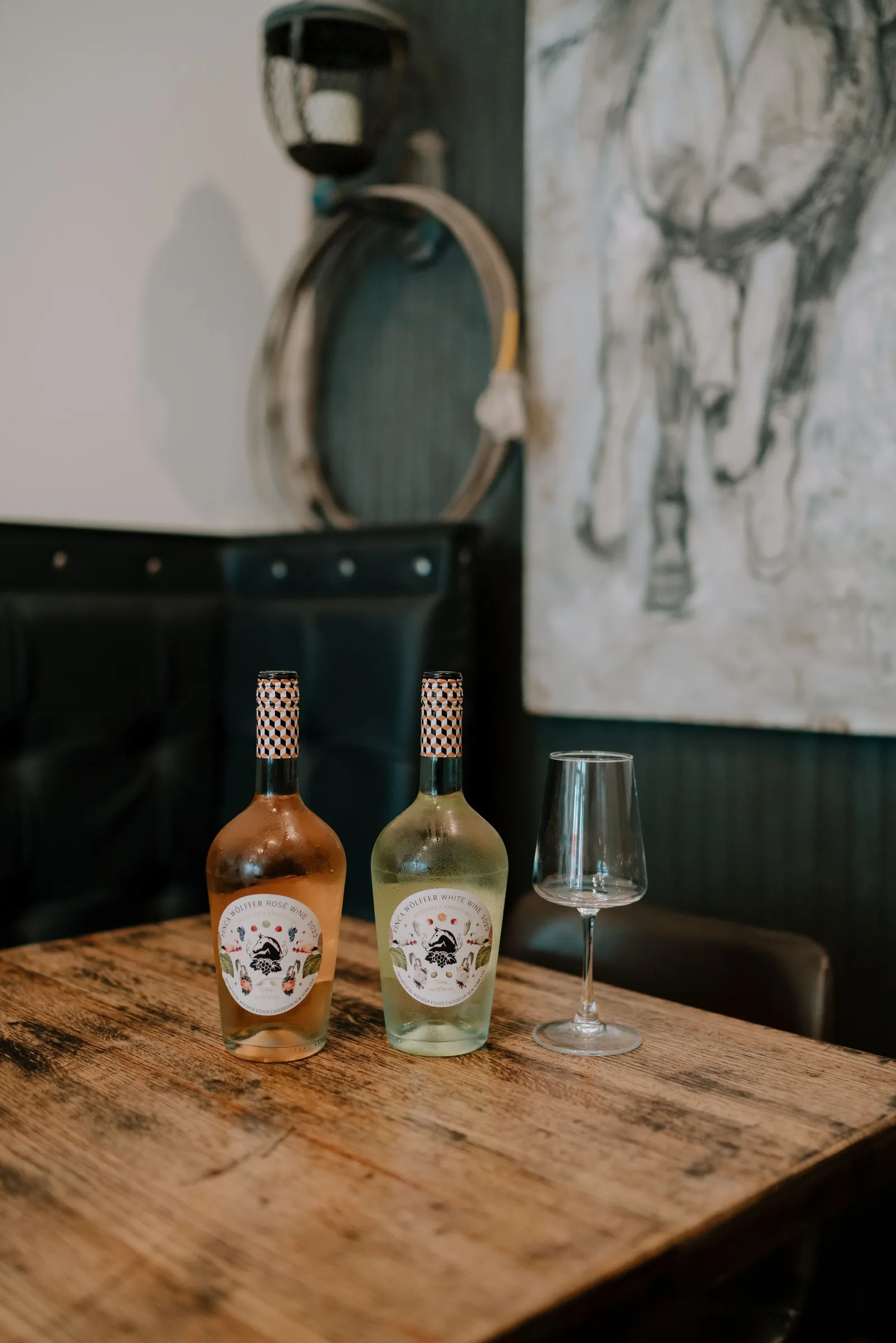 A framed horse drawing above a table set with wine at Criollo