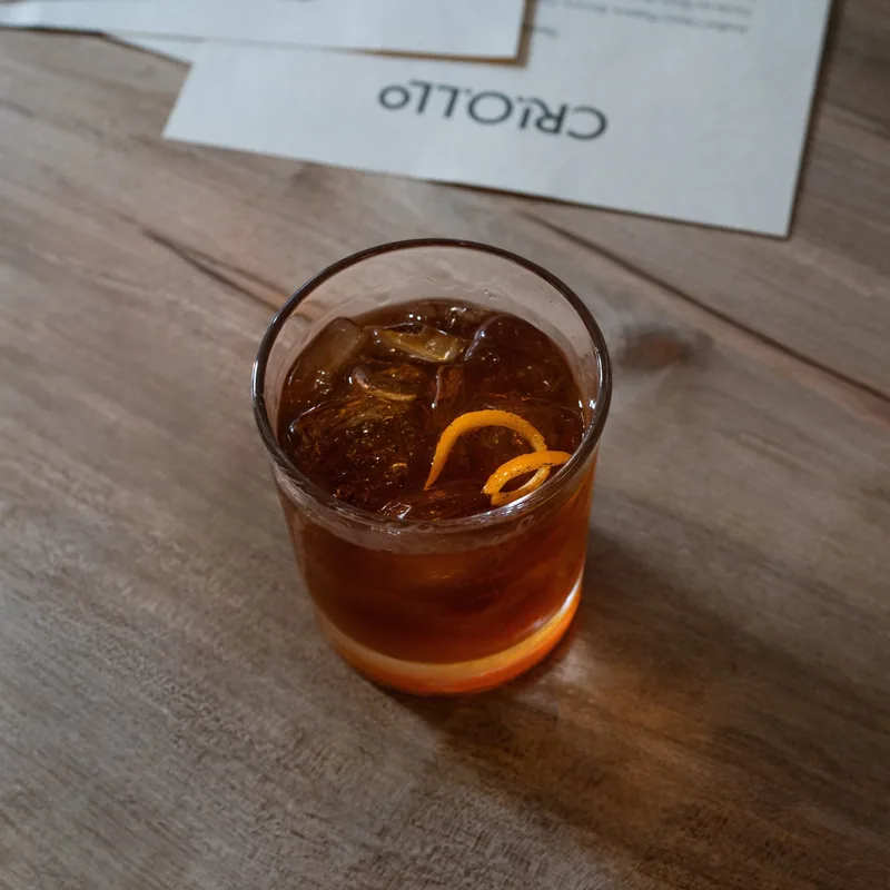 An old fashioned with an orange twist on a wooden table