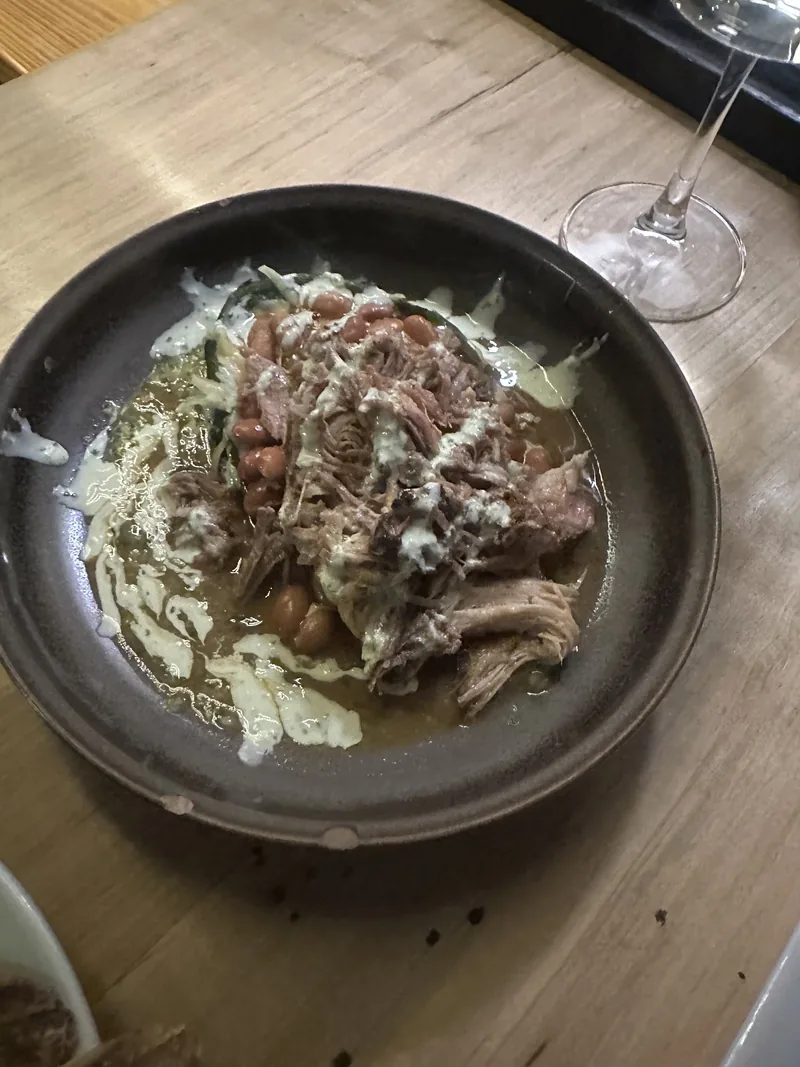 A skillet dish of pulled pork with crema